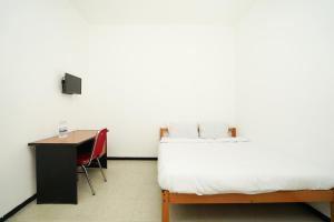 a bedroom with a bed and a desk and a table at Merapi Inn Syariah by ecommerceloka in Surabaya