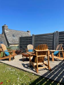 eine Terrasse mit 3 Stühlen, einem Holztisch und Stühlen in der Unterkunft Le Courlis in Guimaëc