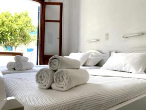 two white towels are stacked on a bed at Helliniko Studios in Parikia