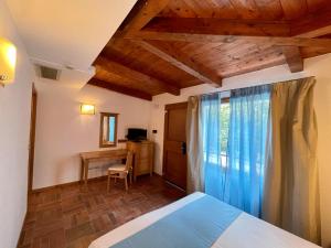 Schlafzimmer mit einem Bett, einem Schreibtisch und einem Fenster in der Unterkunft Le Mandrelle Beach Resort in Amantea