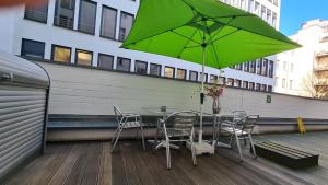 a table and chairs with a green umbrella on a balcony at Hotel Cristall - Frankfurt City in Frankfurt/Main