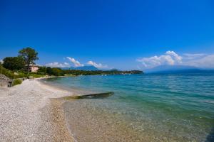 a beach with clear water and a rocky shore at Apparthotel San Sivino in Manerba del Garda