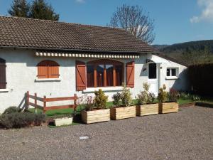 ein weißes Haus mit einer Bank und einigen Pflanzen in Holzkisten in der Unterkunft La Campagnarde in Saint-Just-en-Chevalet