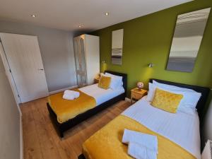 two beds in a room with green walls at 144 - ExcellentStays - 2 Bedroom Flat in Stanwell