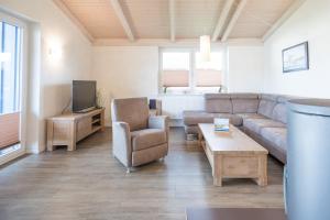 ein Wohnzimmer mit einem Sofa, einem Stuhl und einem TV in der Unterkunft Ferienhaus Süderoog in Dagebüll