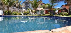 a swimming pool in front of a house with palm trees at Apartamentos beira mar in Porto De Galinhas