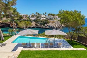 a pool with chairs and umbrellas next to the water at Villa Magdala in Portopetro