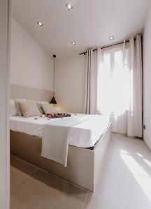 a white bedroom with a large bed and a window at Le Beach in Saint-Tropez