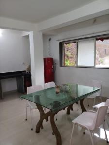 a dining room with a glass table and white chairs at Vamoose Swara Niwas Bungalow in Mahabaleshwar