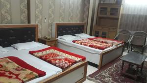 two beds in a bedroom with chairs and a table at Vamoose Suri Rudraprayag in Badrīnāth