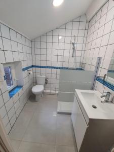 a white tiled bathroom with a toilet and a sink at APPARTEMENT AGATHOIS-3 in Agde