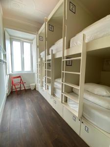 um quarto com beliches e uma cadeira vermelha em Green Heart Hostel em Lisboa