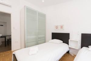 a white bedroom with two beds and a desk at Apartment near the beach with big terrace in Setúbal