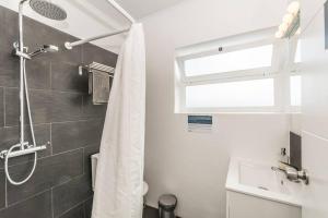a white bathroom with a shower and a sink at Apartment near the beach with big terrace in Setúbal