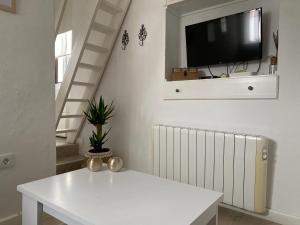 ein Wohnzimmer mit einem weißen Tisch und einem Fernseher in der Unterkunft Casa Romántica "La CHELA" in Vejer de la Frontera