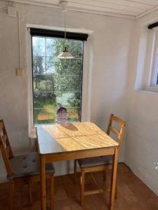 a wooden table and chairs in a room with a window at Mysigt gästhus med cykelavstånd till havet! in Skivarp