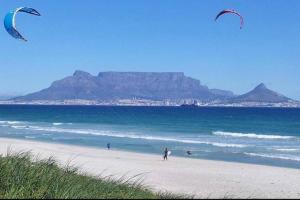 two people on a beach flying kites on the beach at Waters Breakaway in Bloubergstrand