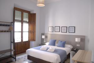 a bedroom with a large bed with blue pillows at La Perla Granada Suites in Granada