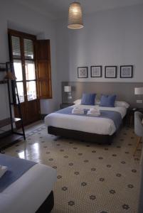 a bedroom with two beds with blue pillows at La Perla Granada Suites in Granada