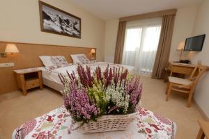 a hotel room with a bed and flowers on a table at Hotel Alpejski in Polanica-Zdrój