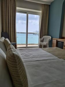 a bedroom with a bed and a view of the ocean at Water's Edge Hotel in Birżebbuġa
