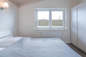 a white bedroom with a bed and a window at Ferienhaus Süderoog in Dagebüll