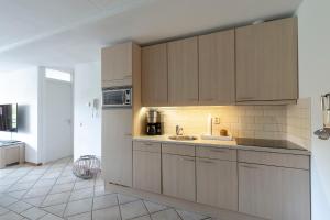 een keuken met houten kasten en een wastafel bij Wijde Blick appartement 211 - Callantsoog in Callantsoog