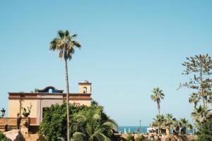 a building with palm trees and the ocean in the background at Europe Villa Cortes GL in Playa de las Americas
