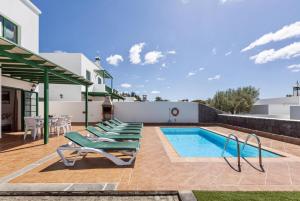 een patio met ligstoelen en een zwembad bij Villa Costa Papagayo 6 in Playa Blanca