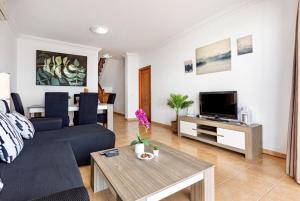 ein Wohnzimmer mit einem blauen Sofa und einem TV in der Unterkunft Villa Costa Papagayo 6 in Playa Blanca