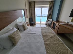 ein Hotelzimmer mit einem großen Bett und einem Schreibtisch in der Unterkunft Water's Edge Hotel in Birżebbuġa