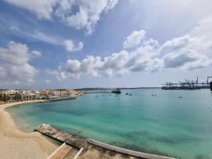 a view of a beach with boats in the water at Water's Edge Hotel in Birżebbuġa