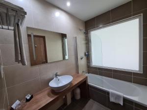 a bathroom with a sink and a tub and a window at Water's Edge Hotel in Birżebbuġa