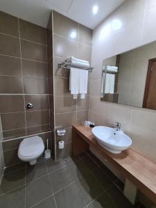 a bathroom with a sink and a toilet and a mirror at Water's Edge Hotel in Birżebbuġa