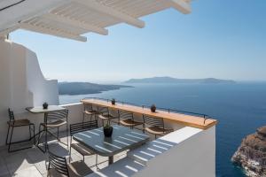 a balcony with a table and chairs and the ocean at Porto Fira Suites in Fira