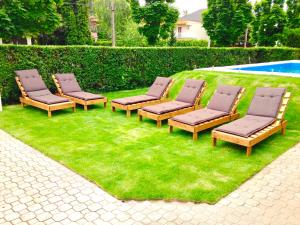 a group of chairs sitting on the grass near a pool at Villa 55 & Pool - Siófok in Siófok