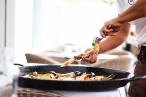 a person is preparing food in a pan at Europe Villa Cortes GL in Playa de las Americas