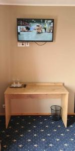 einen an einer Wand hängenden TV mit einem Holztisch in der Unterkunft Šeduvos malūnas in Šiauliai
