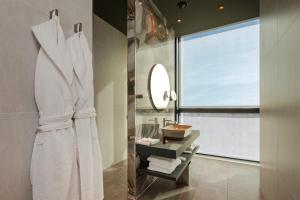 a bathroom with a white robe and a window at ONLY Boutique Suites & Residences in Limassol