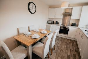 a kitchen with a wooden table with chairs and a clock at The Seafield Arms Hotel Cullen - Self Catering in Cullen