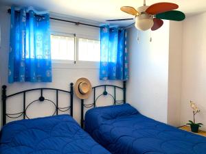 ベナルマデナにあるSkySea Holidays Marina Blueの青いカーテンとファン付きのベッドルーム内のベッド2台