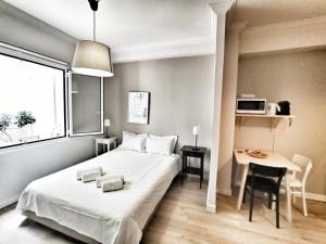 a bedroom with a white bed and a table and a window at Artemis Apartment @ Plaka in Athens