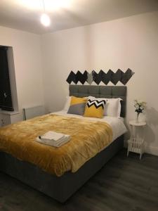 une chambre avec un grand lit avec une couverture jaune dans l'établissement Modern Comfort House On Eamont RD, à Stockton-on-Tees