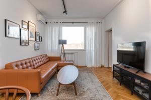 a living room with a brown leather couch and a flat screen tv at Industrial 2-BDR Flat by the National Stadium in Sofia