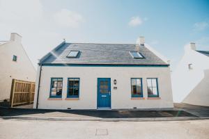 a white house with a blue door on a street at The Seafield Arms Hotel Cullen - Self Catering in Cullen