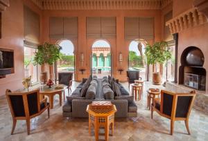 een woonkamer met een bank en tafels en stoelen bij Amanjena Resort in Marrakesh