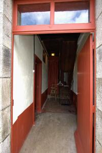 een lege hal met een rode deur en een stoel bij Studio Les Pourettes in Feusines