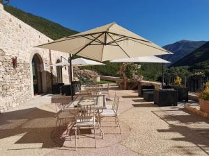 eine Terrasse mit Tischen, Stühlen und einem Sonnenschirm in der Unterkunft Torre Del Nera Albergo diffuso & Spa in Scheggino