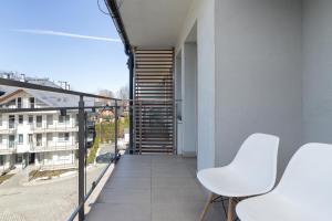 balkon z 2 białymi krzesłami i schodami w obiekcie Stara Polana Apartamenty & Spa Zakopane by Renters w Zakopanem