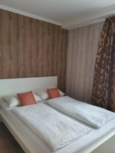 a bedroom with a white bed with red pillows at Hotel Schneider Apartaments in Langenhagen